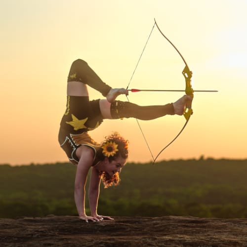 Tiny Girl Big Show doing a handstand and shooting a bow with her feet