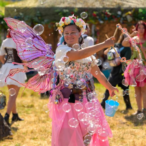 A woman dressed like a fairy surrounded by bubbles